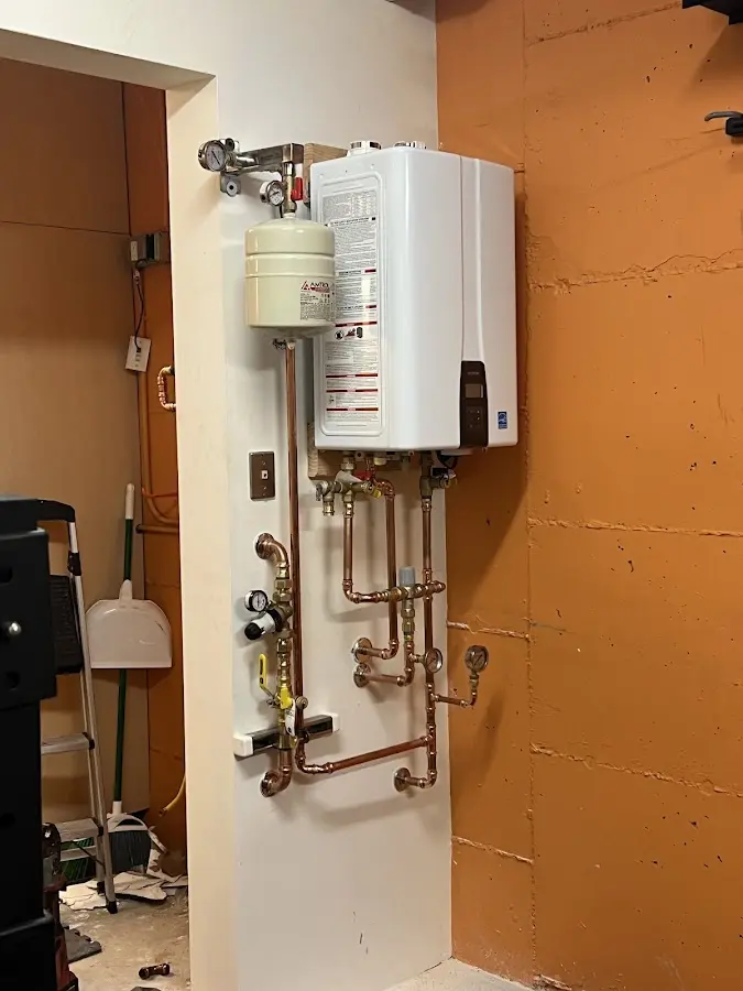 Plumbing technician inspecting water heater connections in Belding